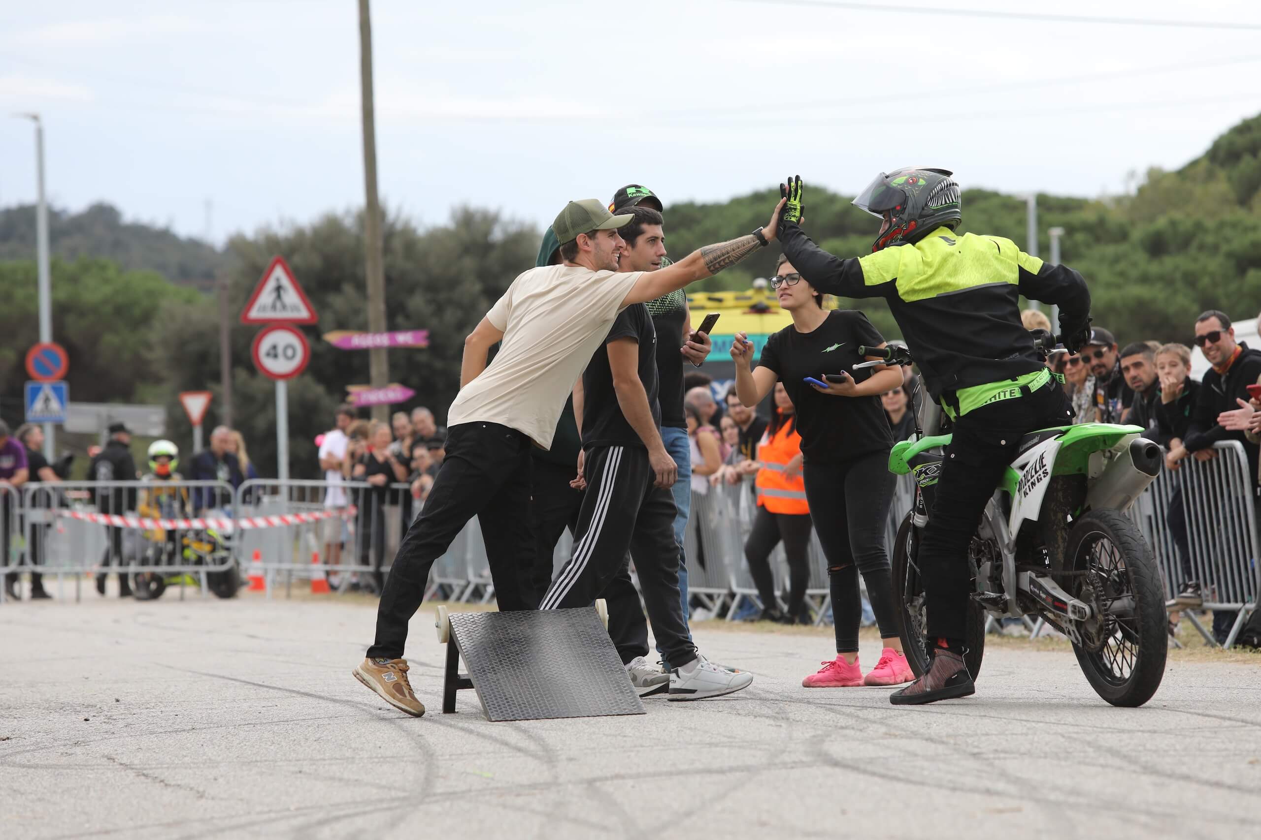 Saludo y choque de manos con fans junto a la Kawasaki KXF tras un salto